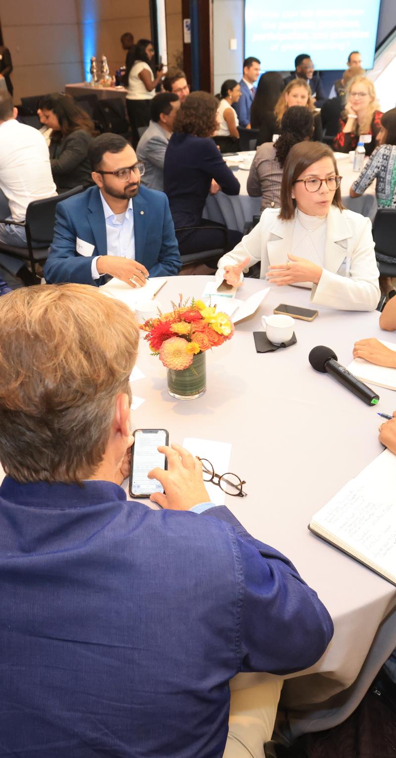 A group of diverse adults sit around a table in discussion 