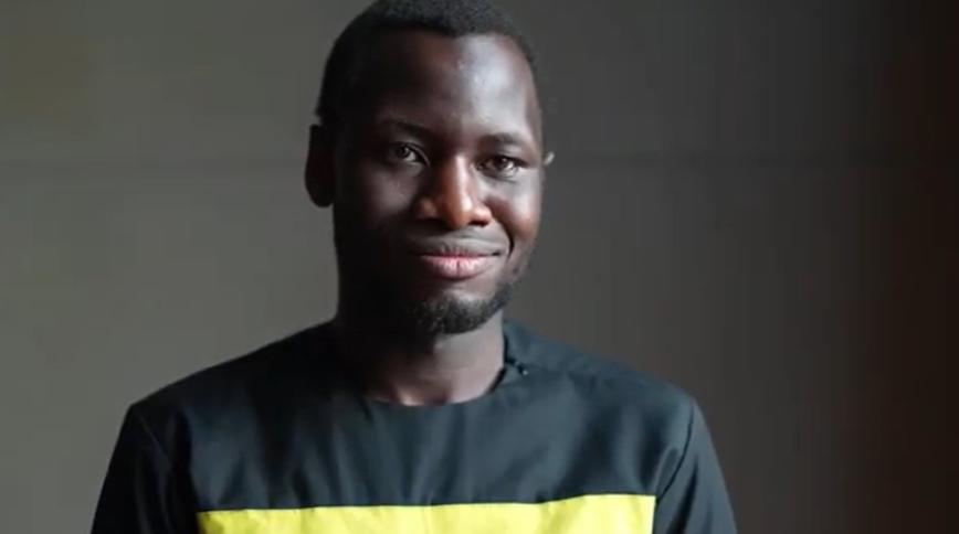Tight headshot of a young black man in a black t-shirt